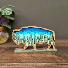 Load image into Gallery viewer, Wooden buffalo sculpture with a mountain and forest design on a wooden surface