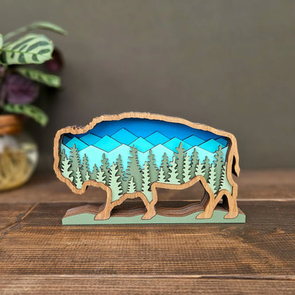 Wooden buffalo sculpture with a mountain and forest design on a wooden surface