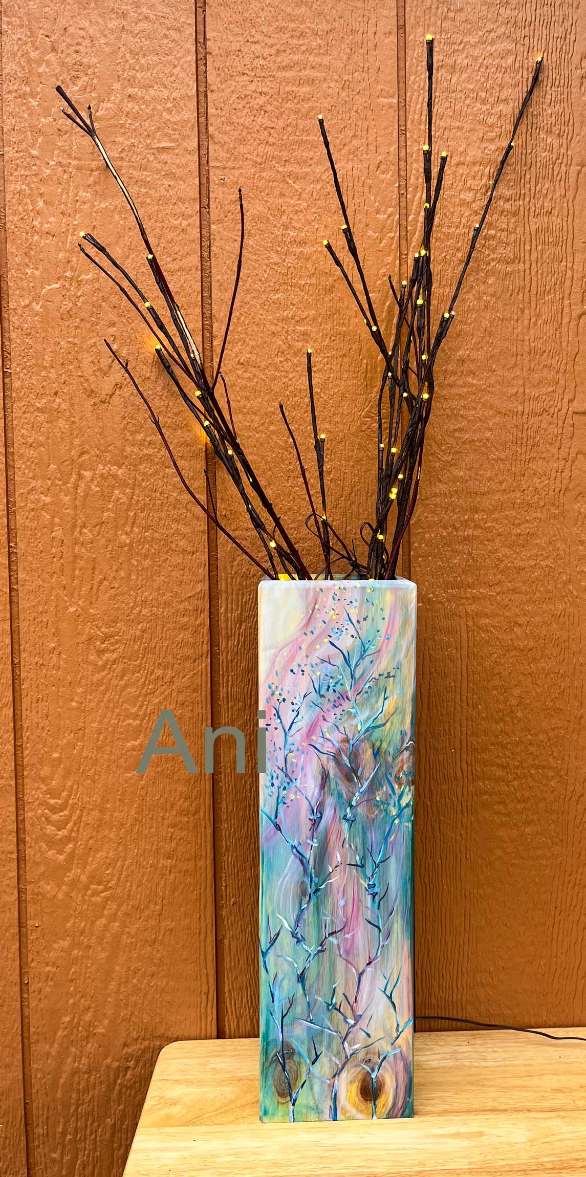 Vase with floral design and branches against a wooden background